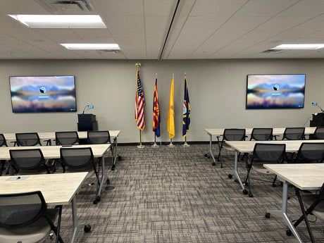 ATF Phoenix Field Division training room with dual wall-mounted displays flanking American, Arizona, and ceremonial flags, with classroom-style seating, in Phoenix, Arizona.