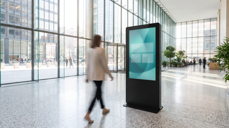 Freestanding portrait-orientation interactive touchscreen kiosk enclosure in a bright commercial lobby