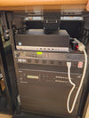 Classroom lectern rack in Building 1900 with an HP EliteDesk PC, a Listen Technologies LT-800 assistive listening transmitter, a Tripp-Lite power strip and a Crestron DMPS3-300-C presentation system