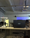 Instructor desk in a Diablo Valley College ATC classroom in Pleasant Hill, with a Planar PLN2501 monitor, a ceiling-mounted projector and Bose DM5SE loudspeakers either side of the projection screen.