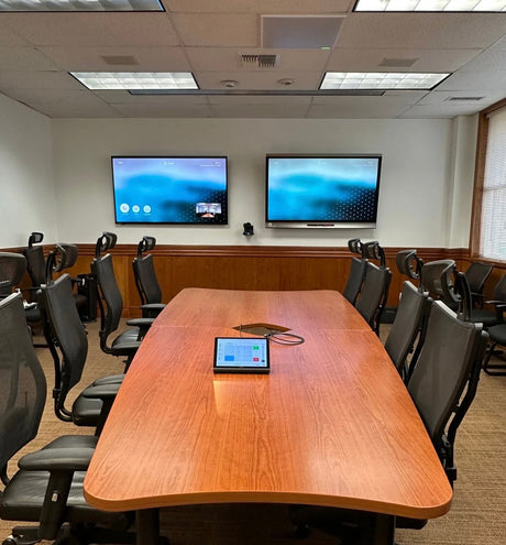 FEMA Region 9 Pacific Area Office conference room in Honolulu, Hawaii, with dual wall displays running Poly video conferencing, a PTZ camera between them, and a Crestron tabletop touch panel on the conference table.