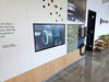 The Electric Adventure wall panel at Rivian's Franklin, Tennessee showroom, with a 43-inch Planar SLP43-T touch display flush-mounted in the graphic wall beside a Rivian wall charger.
