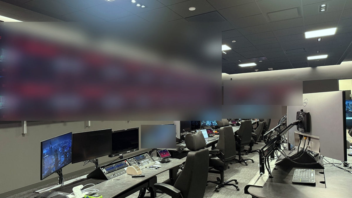 Twenty Sony FW65BZ40L displays in a two-row control room video wall with a tilted top row and QSC AD-S8T loudspeakers above, facing operator consoles in the Netflix Live Command Center in Los Gatos, California.
