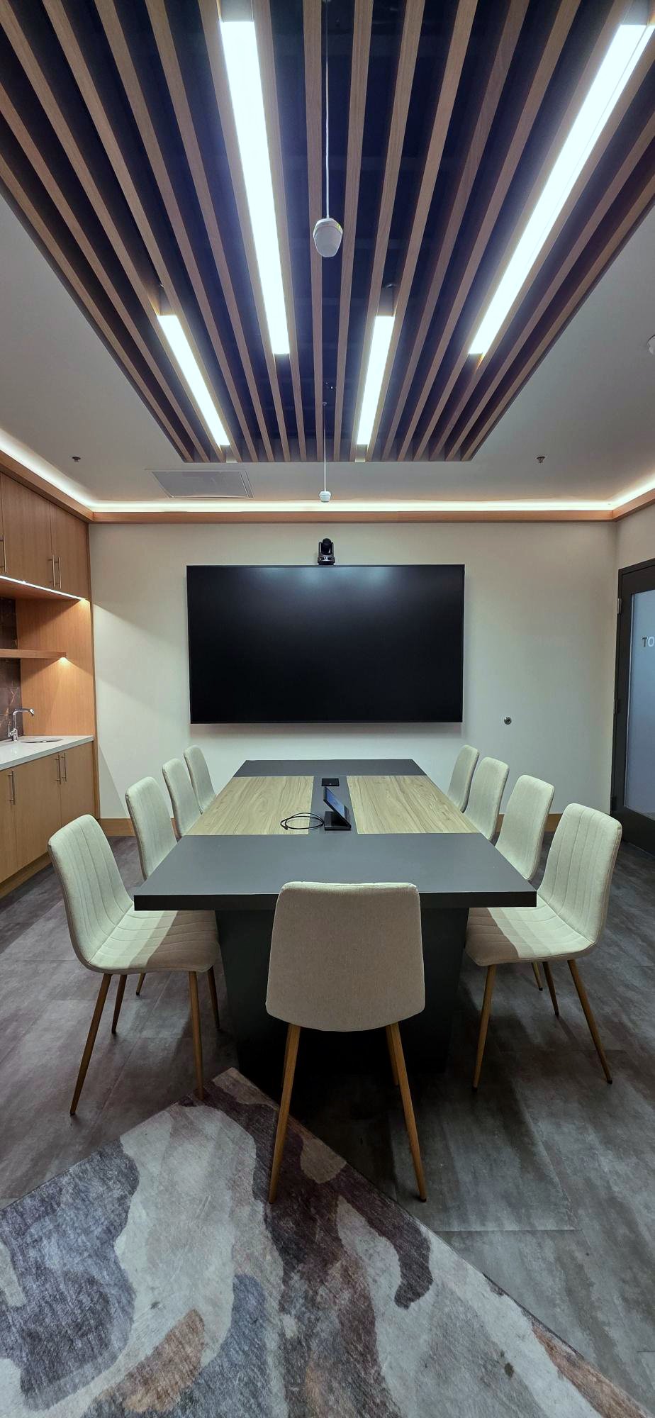 NBA VIP suite at Pivot Sports Bar Pleasanton with a 98-inch display, PTZ camera above it and a Biamp pendant beamtracking microphone over the conference table