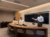 Three people in a modern conference room discussing at a curved table.