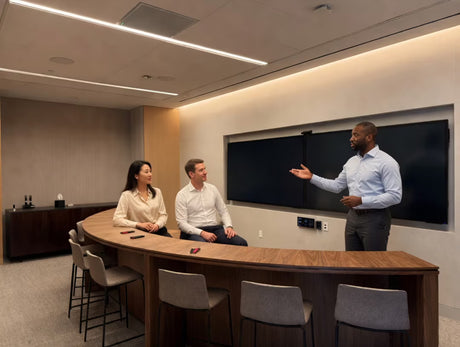 Three people in a modern conference room discussing at a curved table.