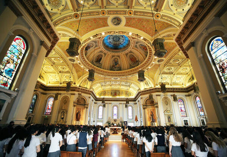 Interior of a grand church filled with worshippers and ornate architecture.