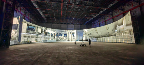 Large, empty industrial space with screens and two people.
