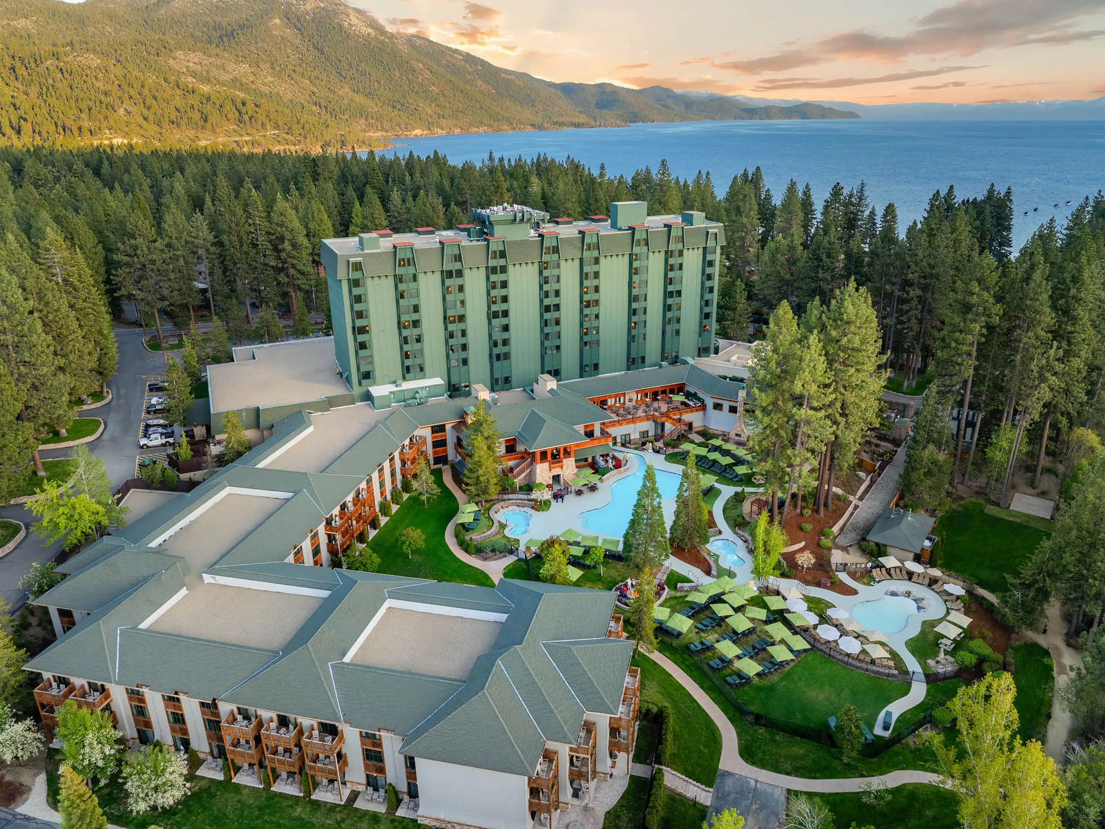 Aerial view of a hotel complex near a lake surrounded by trees.