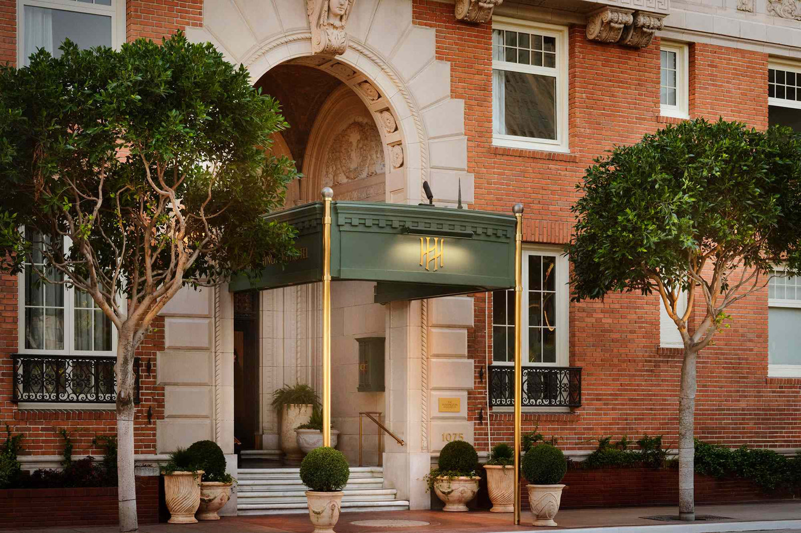 Entrance of a brick building with trees and a green awning.